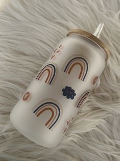 a white cup with rainbows on it sitting on top of a fur covered floor