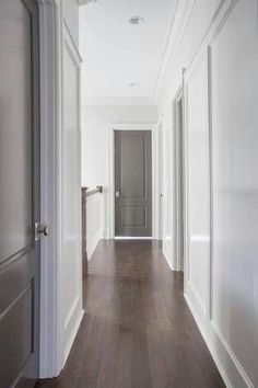 an empty hallway with white walls and wood floors