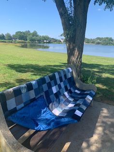 a blue and white checkered blanket sitting on top of a bench next to a tree