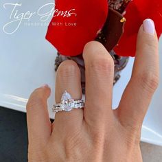 a woman's hand with a diamond ring on it and a rose in the background