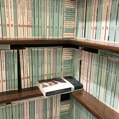 a bookshelf filled with lots of green and white books