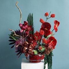 a vase filled with red flowers on top of a white cake covered in greenery