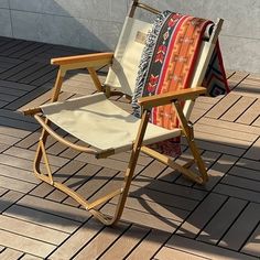 a wooden chair with a blanket on it sitting on a brick floor next to a wall