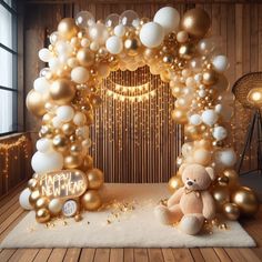 a teddy bear sitting under a balloon arch