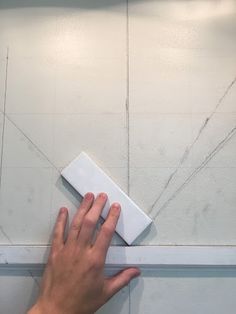 a person's hand is on the edge of a wall with a white square object