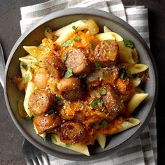 a bowl filled with pasta and meatballs on top of a white cloth next to a fork