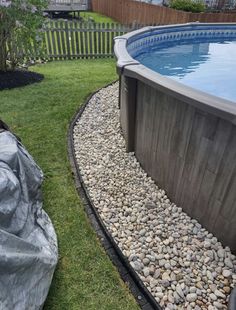 an above ground swimming pool surrounded by rocks and gravel with a fence in the background