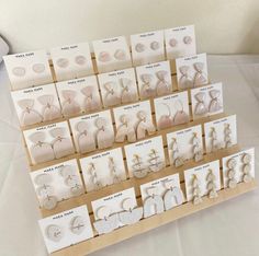 there are many pairs of earrings displayed on the display stand with cards in front of them