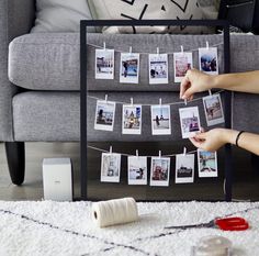 a woman is hanging pictures on a clothes line with her hands and sewing needles next to it