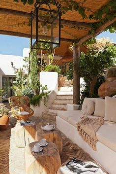 an outdoor living area with white couches and wooden tables