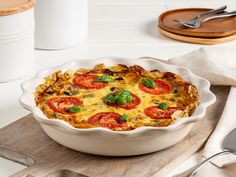 a casserole dish with tomatoes and spinach in it on a cutting board