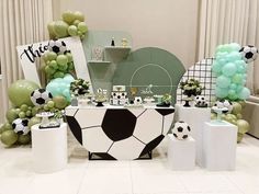 a table topped with lots of balloons and soccer themed decorations on top of a white floor