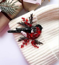 a bird brooch sitting on top of a white sweater next to christmas decorations and presents