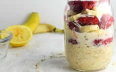 a jar filled with granola and fruit on top of a table next to a banana