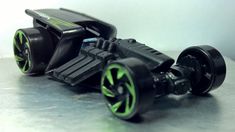 a black toy car with green wheels on a table