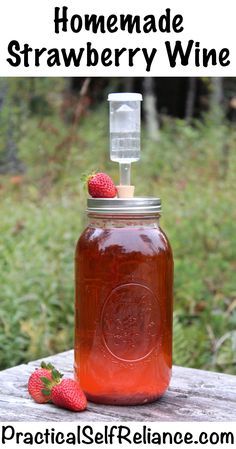 homemade strawberry wine in a mason jar with strawberries on the side and text overlay