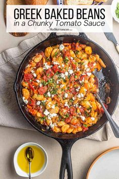 a skillet filled with greek baked beans in a creamy tomato sauce and topped with feta cheese