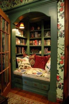 a room with green bookshelves and floral wallpaper on the walls in it