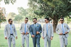 a group of men standing next to each other wearing suits and sunglasses on their heads