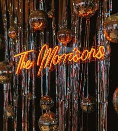 disco balls hanging from the ceiling in front of a neon sign that reads, the moussons