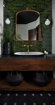 a bathroom with green brick walls and a large mirror on the wall above the sink