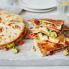 a stack of quesadillas sitting on top of a cutting board next to a plate