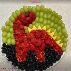 a plate with grapes, strawberries, and other fruit arranged in the shape of a dinosaur