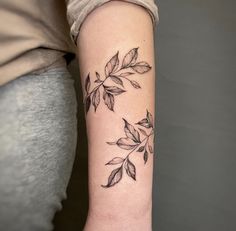 a woman's arm with leaves on it