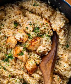 chicken and rice in a skillet with a wooden spoon on the side, garnished with parsley