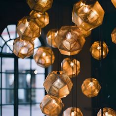 a bunch of lights hanging from the ceiling in a room next to a large window