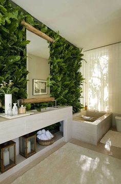 a bathroom with plants on the wall and a bathtub in the middle, along with a mirror