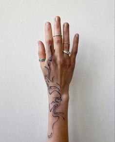 a woman's hand with a tattoo on her left wrist and the other arm