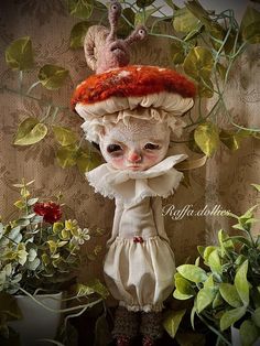 a doll with red hair wearing a white dress and hat next to some potted plants