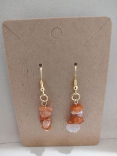 Handcrafted dangle earrings featuring natural carnelian chip beads in warm sunset hues. Gold-toned fishhook earwires. These lightweight earrings add a touch of earthy elegance to any outfit. Perfect for everyday wear or special occasions. CopyRetry Orange Natural Stones Drop Earrings, Orange Natural Stone Drop Earrings, Adjustable Carnelian Earrings With Natural Stones, Amber Carnelian Earrings With Ear Wire, Adjustable Carnelian Dangle Earrings, Earthy Elegance, Sunset Hues, Warm Sunset, Boone Nc