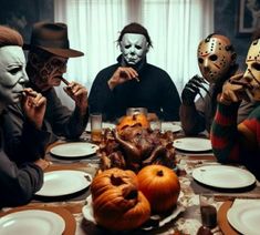 five people sitting at a dinner table with masks on their faces and plates in front of them