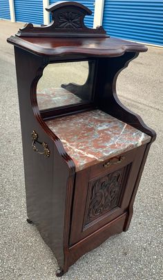 an old wooden cabinet with marble top on the sidewalk in front of a blue building