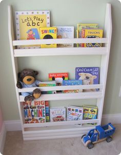 a white book shelf with books and toys on it