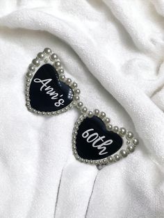 two black and white heart shaped brooches with personalized names on them