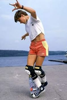 a young man riding a skateboard on top of cement ground next to the ocean