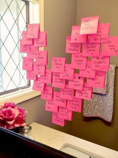 pink sticky notes attached to a mirror in a bathroom with a sink and window behind it