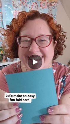 a woman with red hair and glasses making a funny face while holding a piece of paper