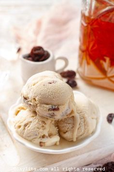 two scoops of ice cream on a plate with raisins next to it