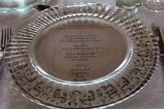 a glass plate with writing on it sitting on a table next to utensils