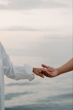 two people are holding hands over the water