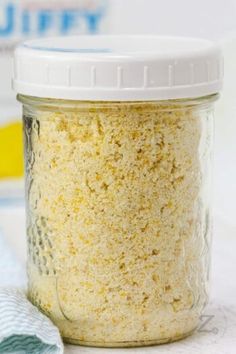 a glass jar filled with yellow powder next to a blue towel on top of a table