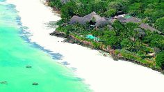 an aerial view of a beach resort with boats in the water and trees surrounding it