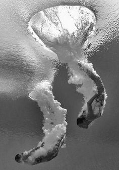 an aerial view of the ocean with two surfers in the water and one is upside down