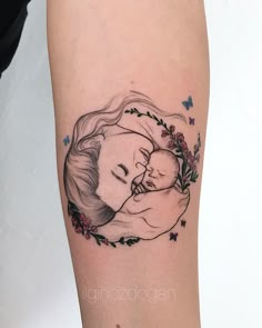 a woman's arm with a tattoo on it that has a drawing of a mother holding her baby