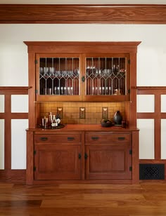 an empty room with wood paneling and glass front cabinets on the wall, along with hardwood flooring