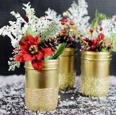 three gold jars filled with flowers and pine cones on top of a snow covered surface